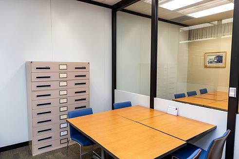 A study room at Orion Library that has a table and four chairs. One wall has a window through which the study room next to it is shown with a table and chairs.