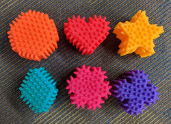 different shapes of plastic balls with prominent textures. The shapes are a circle, heart, star, diamond, snowflake, and four combined circles.