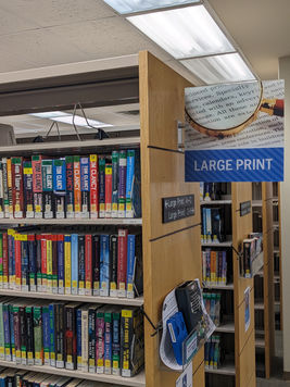The section of the orion library with bookstacks and a sign on one that reads "Large Print" 