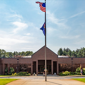 Exterior of the front of orion library building showing the american and michigan state flag post on a sunny day
